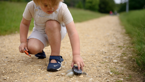 A child plays with a toy car on a path at Stowe Gardens